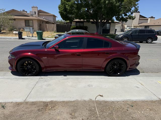 Dark red Dodge Charger with black hood, side profile on a residential street