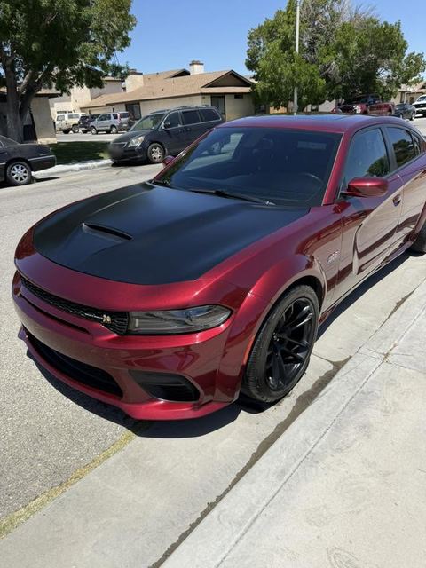 Dark red Dodge Charger with black hood, front three-quarter view on a residential street