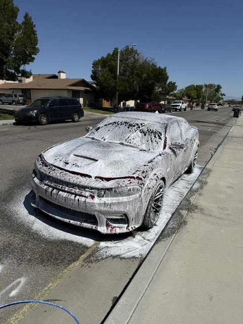 Dodge Charger covered in white wash foam on a residential street