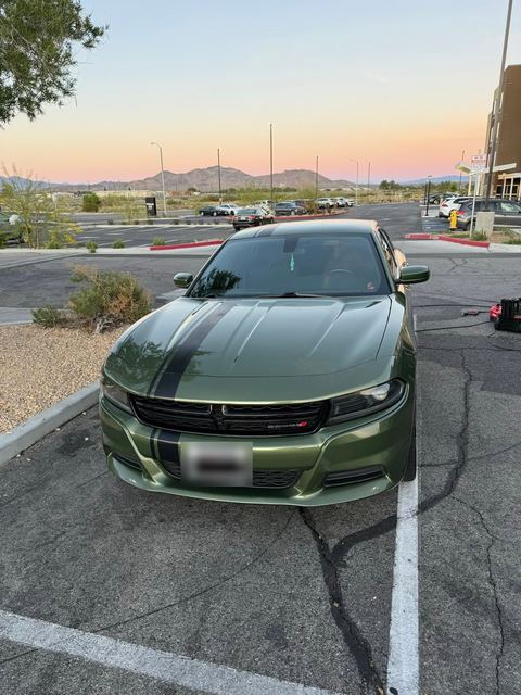 Olive-green Dodge Charger front view in a parking lot at dusk