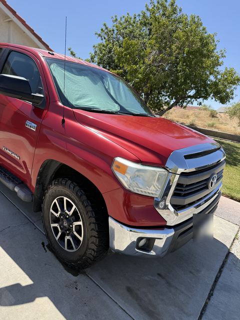 Red Toyota Tundra pickup, front three-quarter view on a driveway