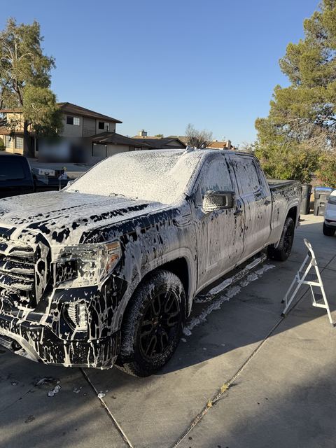 Full-size pickup truck covered in wash foam in a driveway