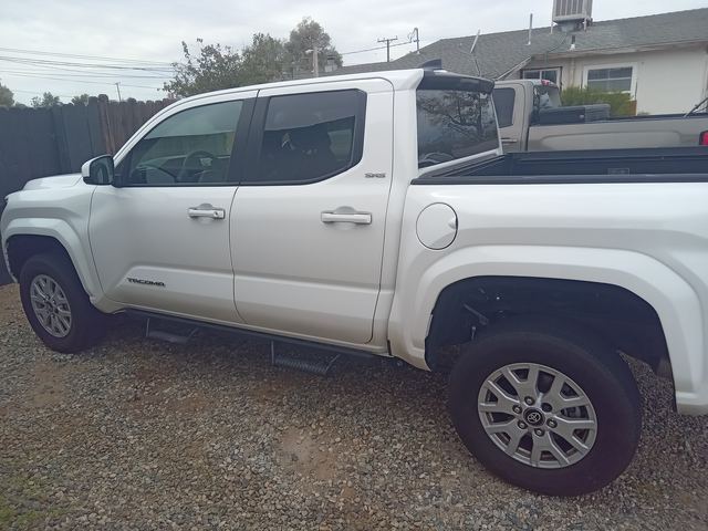 White Toyota Tacoma SR5 crew cab pickup, side view on a gravel driveway